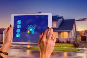 person holding a tablet displaying temperature control to a house